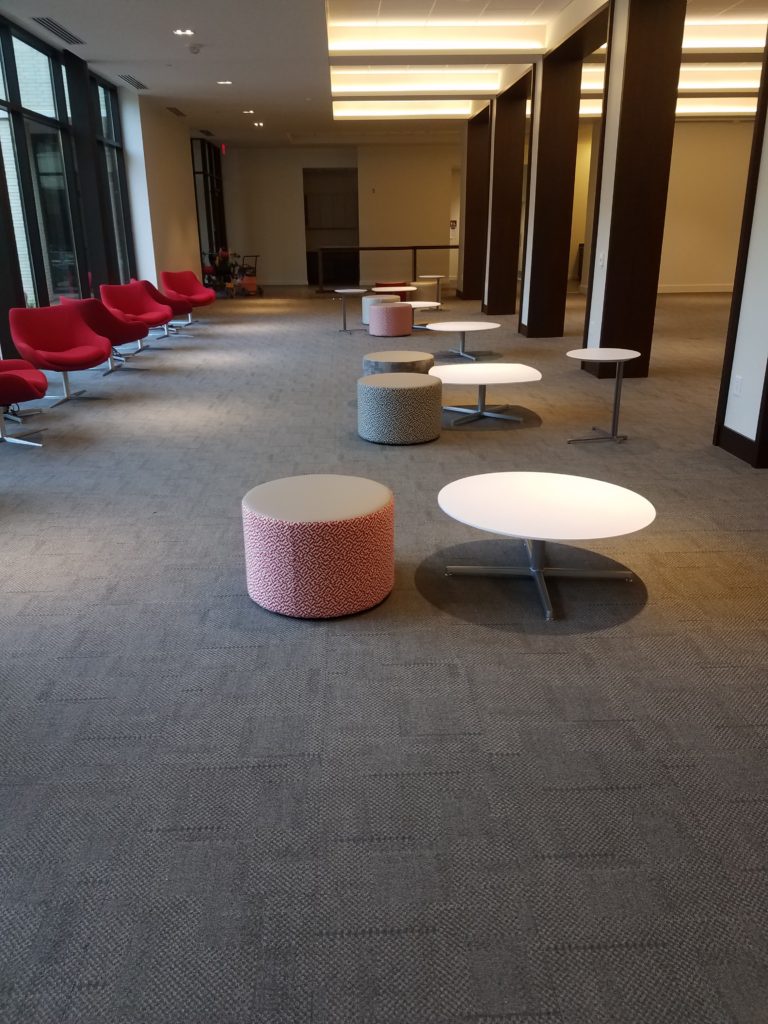 soft red chairs near a glass wall; round ottomans and low tables on carpet