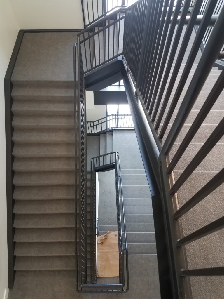 3 stories of carpeted stairs, elongated rectangle staircase with a slight "spiral staircase" effect