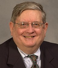 headshot of man in suit with glasses